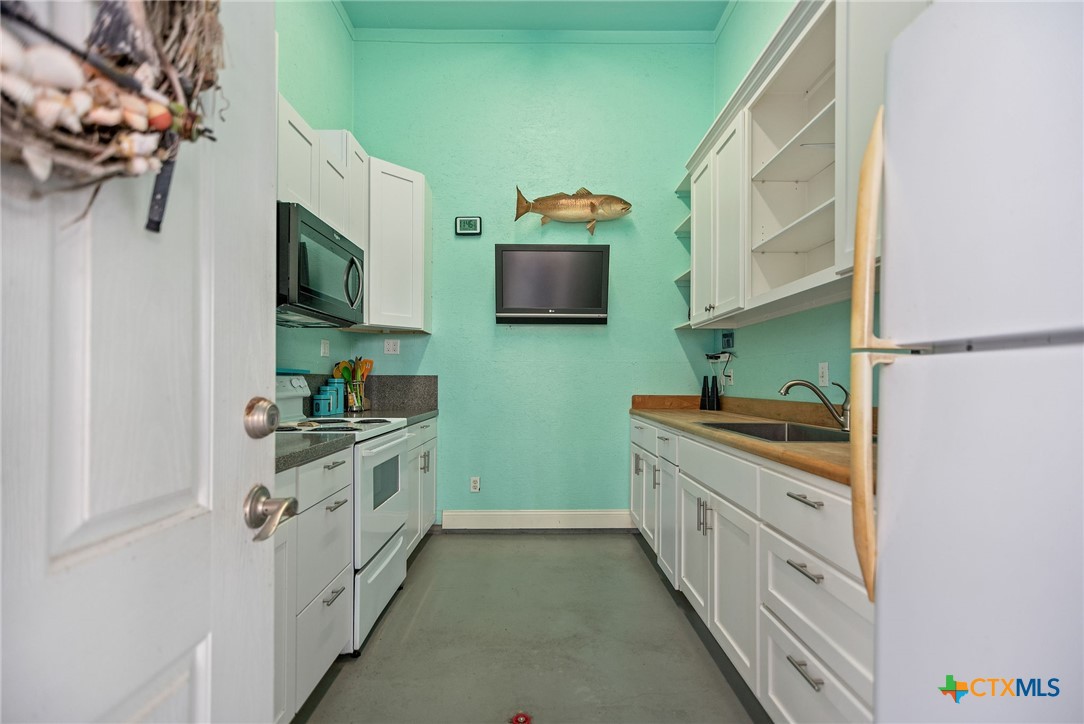 23 Macey Street Port O'Connor, TX 77982 - Photo 13 of 47 a kitchen with granite countertop a sink and a stove top oven