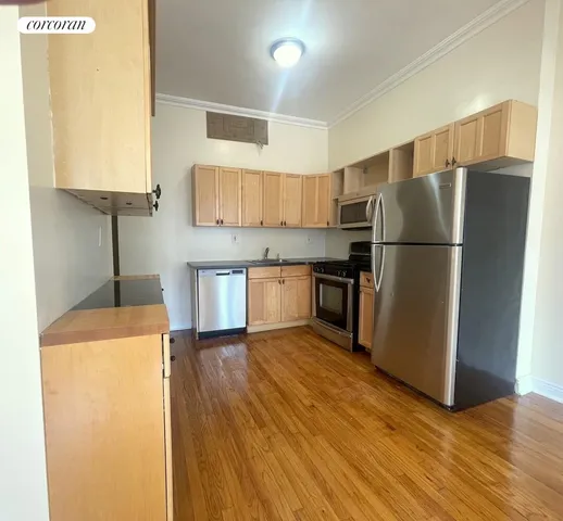 a kitchen with stainless steel appliances granite countertop a refrigerator a stove and a sink with wooden floor