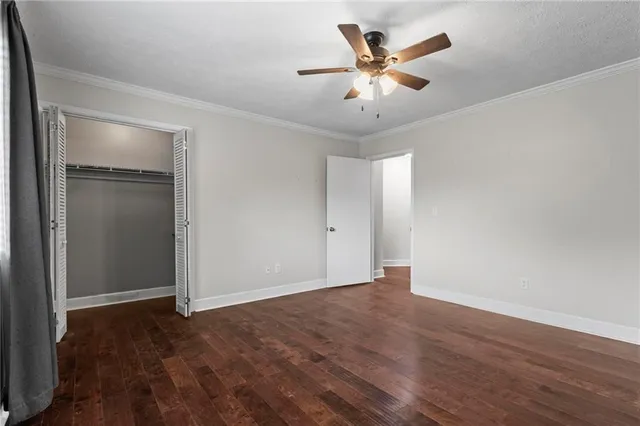 an empty room with wooden floor and ceiling fan