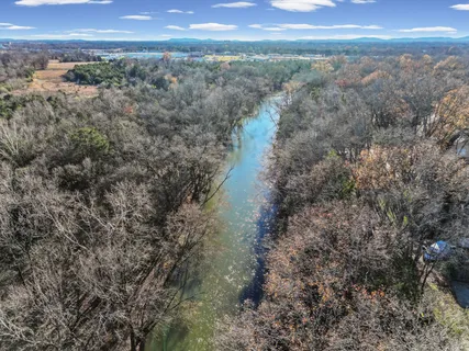 an empty room with wooden floor chandelier and windows