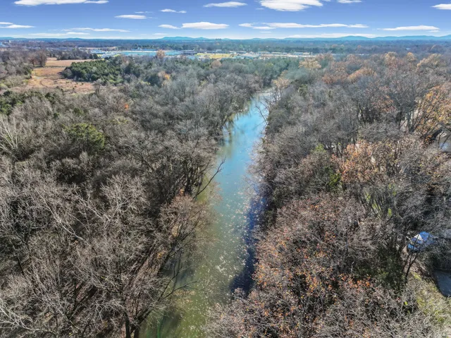 an empty room with wooden floor chandelier and windows