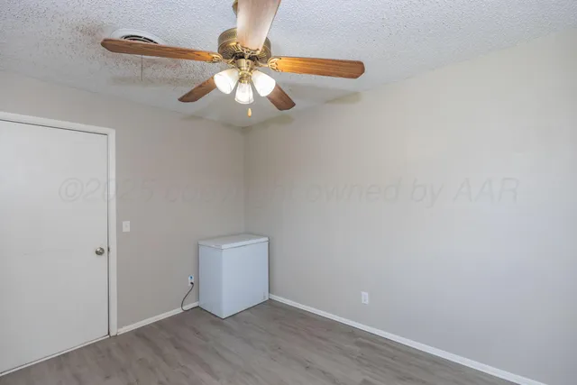 an empty room with wooden floor fan and window