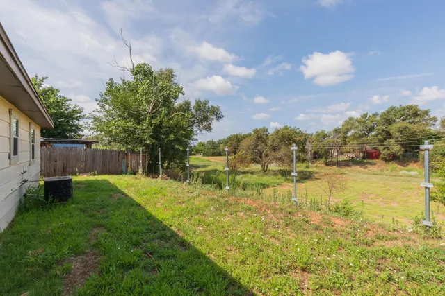 a backyard of a house with lots of green space and lake view in back