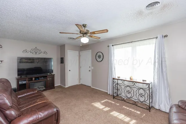 a living room with furniture a flat screen tv and a window