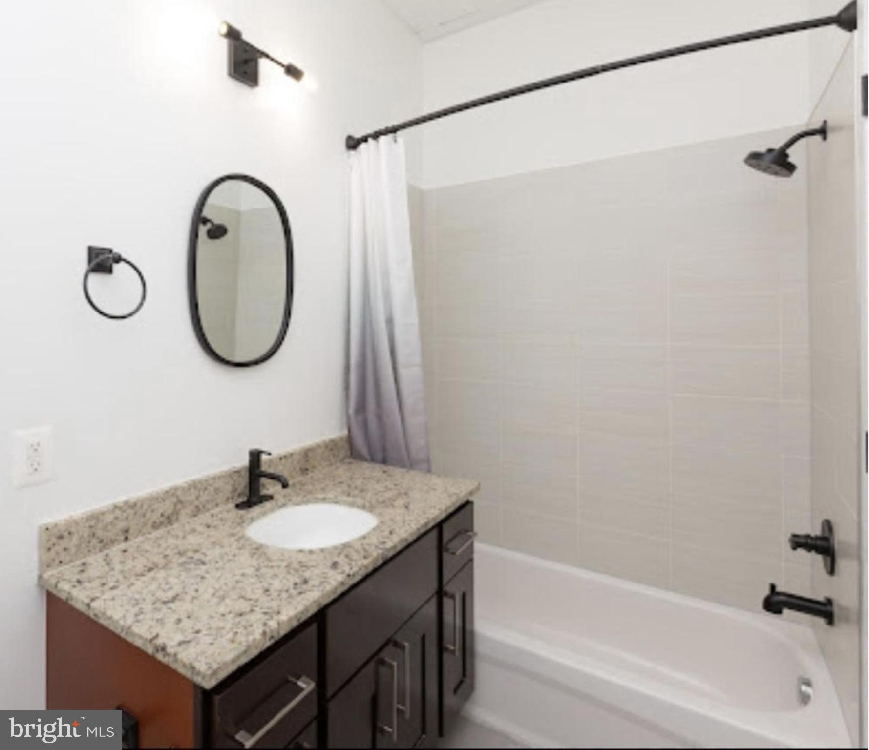 300 Cathedral Street, Unit 106 Baltimore, MD 21201 - Photo 11 of 16 a bathroom with a granite countertop sink and a mirror