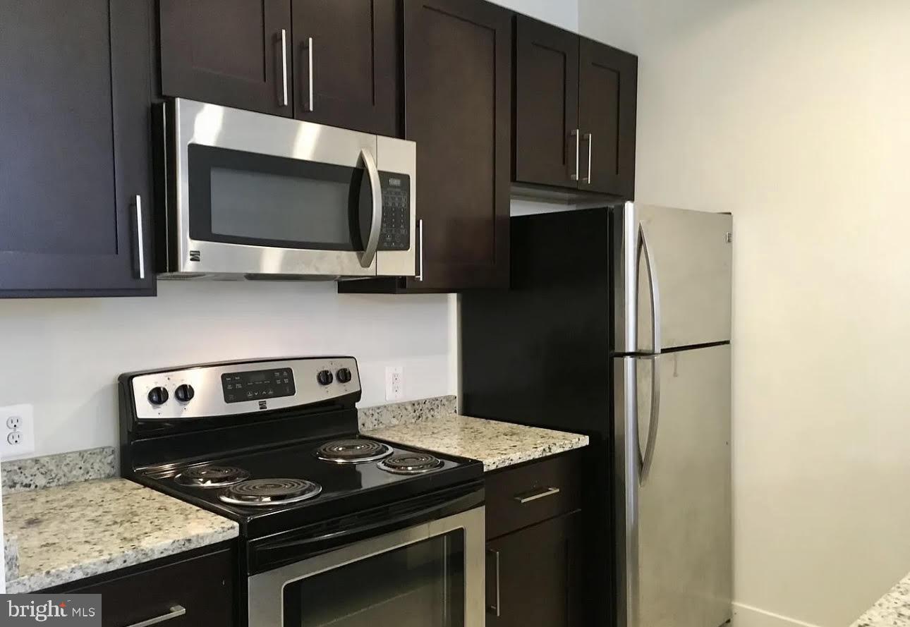 300 Cathedral Street, Unit 106 Baltimore, MD 21201 - Photo 2 of 16 a kitchen with stainless steel appliances a stove a microwave and cabinets