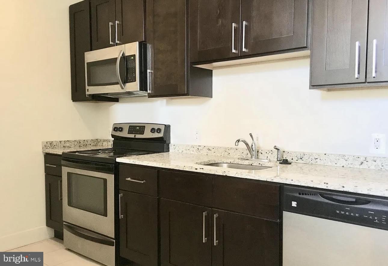 300 Cathedral Street, Unit 106 Baltimore, MD 21201 - Photo 3 of 16 a kitchen with stainless steel appliances granite countertop a sink stove and microwave