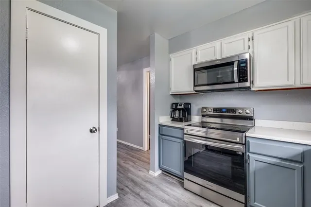 a kitchen with white cabinets stainless steel appliances and a wooden floor