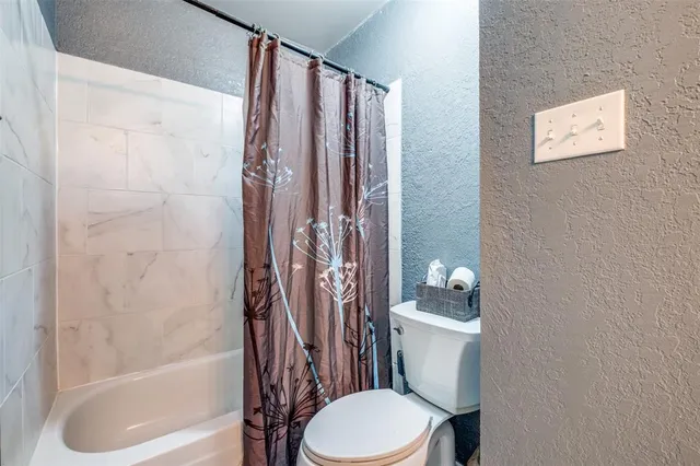 a white toilet sitting next to a bath tub and shower