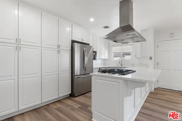 a kitchen with granite countertop a refrigerator a sink and wooden floors