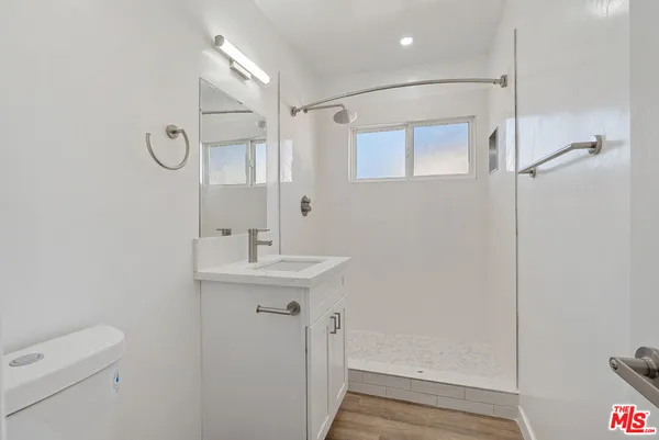 a bathroom with a sink a toilet a mirror and shower