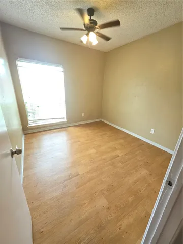 an empty room with a window and a fan