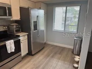 a kitchen with a refrigerator a stove and wooden floor