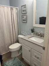 a bathroom with a granite countertop sink toilet and mirror