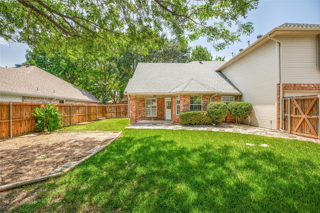 1215 Spring Creek Drive Allen, TX 75002 - Photo 31 of 40 Expansive backyard featuring a brick exterior, stone patio, manicured lawn, and a wooden privacy fence