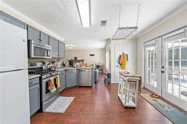 a open kitchen with stainless steel appliances granite countertop a stove refrigerator and a dining table with wooden floor