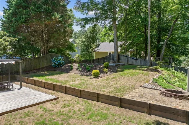 a view of a wooden house with a yard and large trees