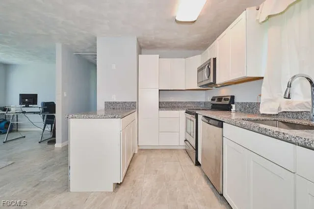 a kitchen with granite countertop white cabinets and white appliances