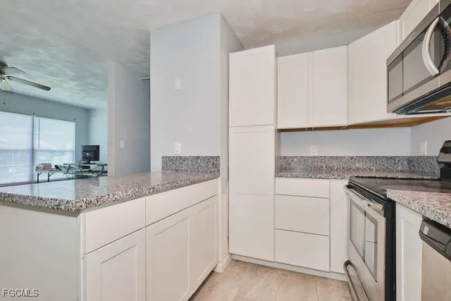 a kitchen with stainless steel appliances granite countertop white cabinets and a sink