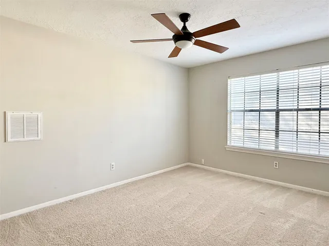 an empty room with a window and a fan