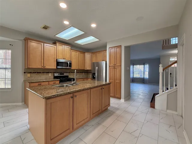 a kitchen with stainless steel appliances granite countertop a refrigerator stove microwave and sink