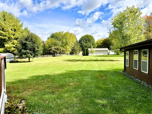 a view of yard with green space and trees in the background