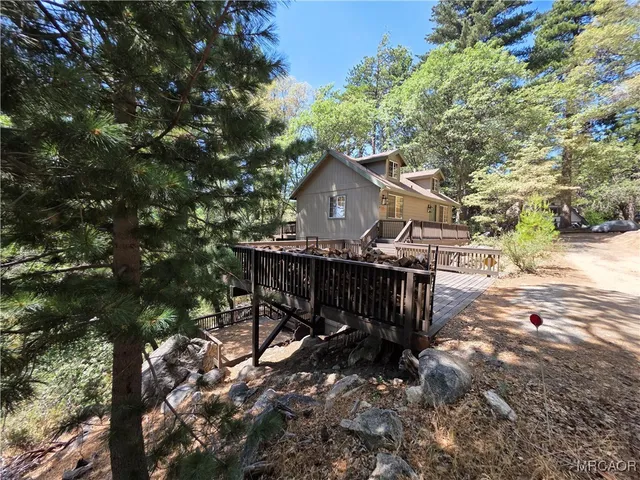 a view of a wooden house with a yard and plants
