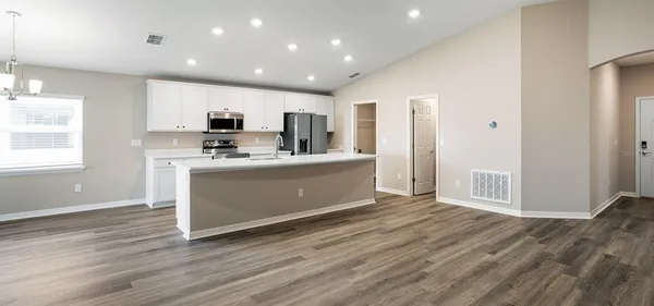 a large white kitchen with kitchen island a sink wooden floor and a refrigerator