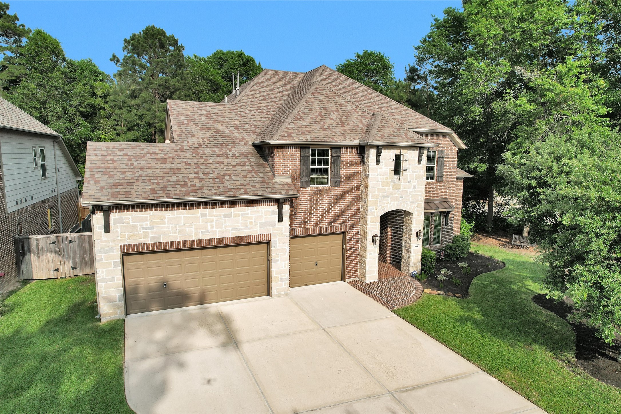 This is a two-story brick and stone house with a three-car garage. It features a well-maintained front yard & spacious driveway, all set in the master planned community of Woodforest
