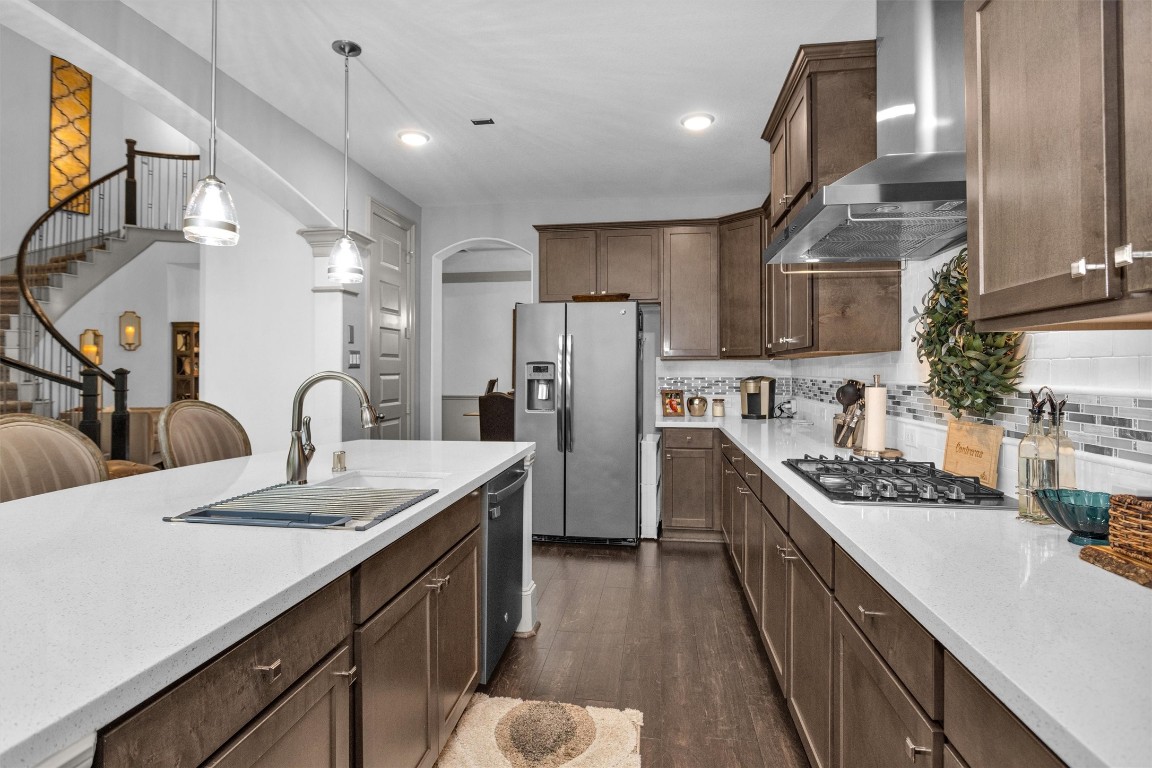 106 Cliftons Curve Way Montgomery, TX 77316 - Photo 20 of 47 This modern kitchen features sleek dark wood cabinetry, stainless steel appliances, and a spacious white countertop island adding elegance and connectivity to the home.