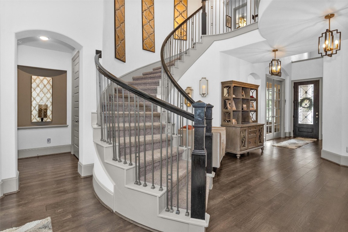 106 Cliftons Curve Way Montgomery, TX 77316 - Photo 23 of 47 Elegant entryway featuring a sweeping curved staircase with sleek railing, warm wood flooring, and stylish light fixtures.