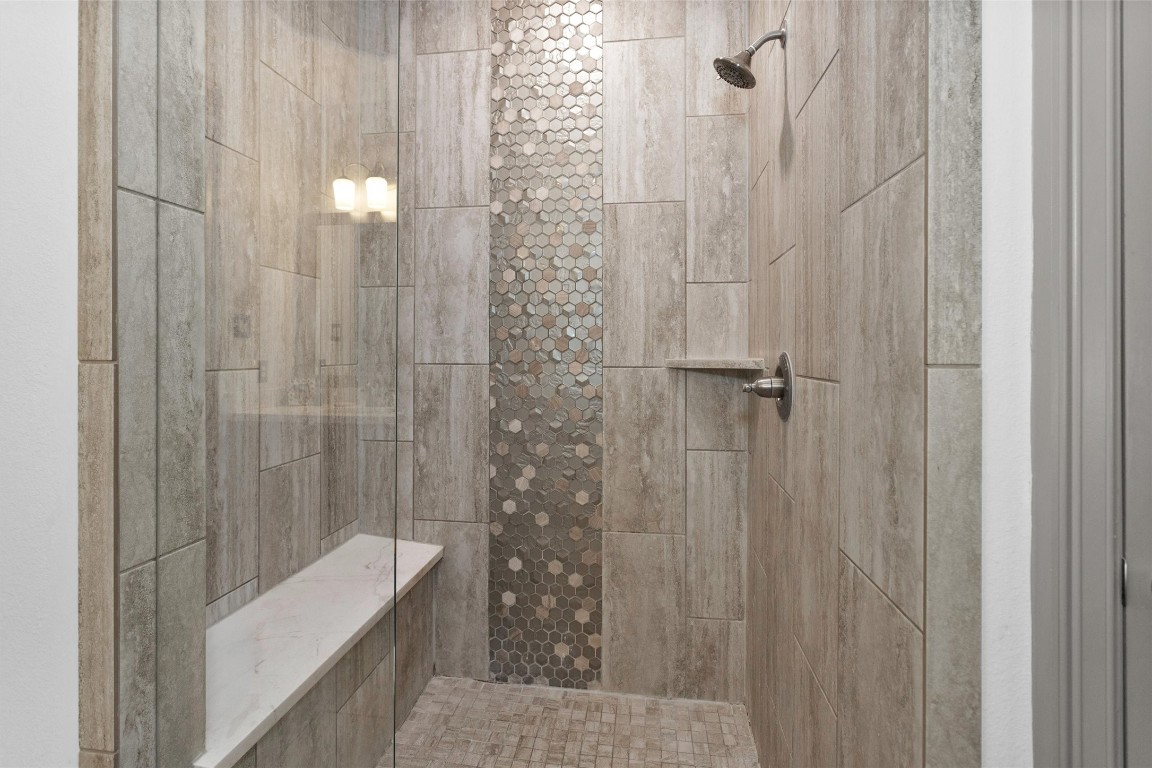 106 Cliftons Curve Way Montgomery, TX 77316 - Photo 28 of 47 Designer walk-in shower featuring textured neutral tiles and a stylish mosaic accent wall. It includes a built-in bench for convenience and a sleek showerhead.