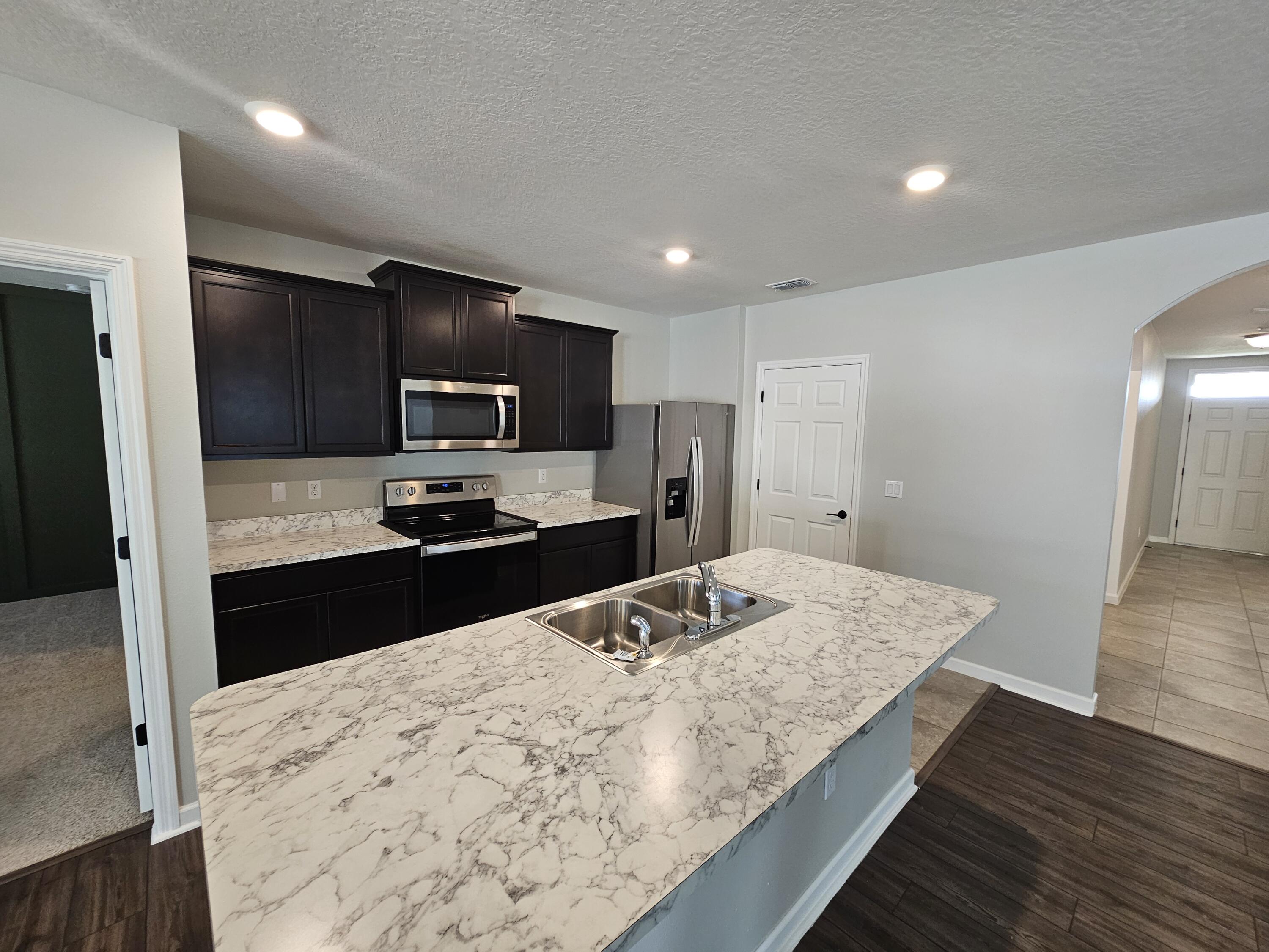 480 Sorrento Drive Cocoa, FL 32922 - Photo 4 of 24 a kitchen with granite countertop wooden cabinets a refrigerator and a sink