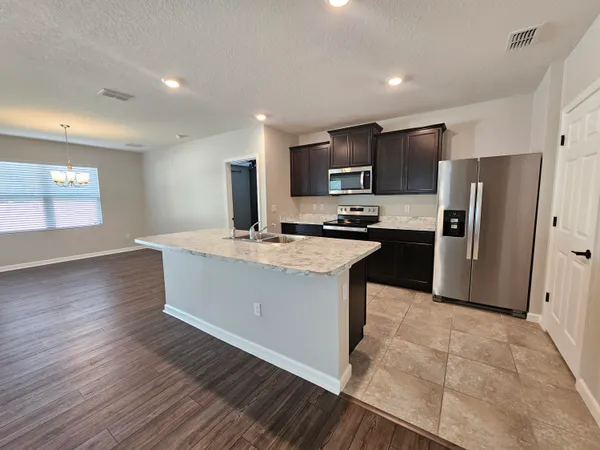 a large kitchen with stainless steel appliances granite countertop a large counter top a sink a refrigerator and a stove