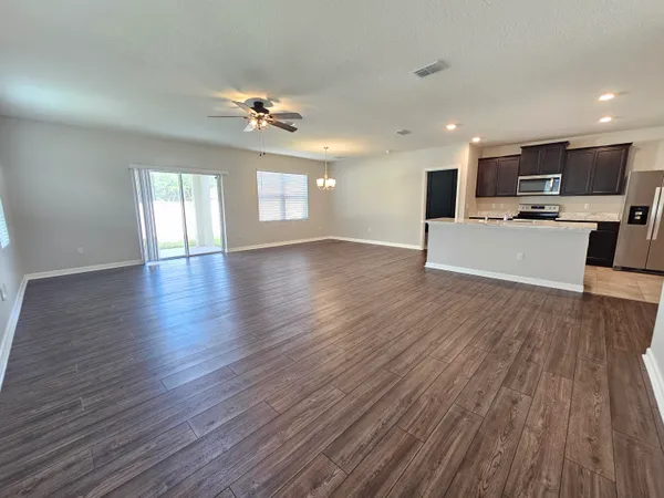 a view of empty room with wooden floor and ceiling fan