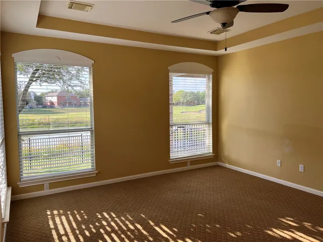a view of an empty room with a window and a ceiling fan