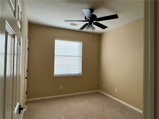 a view of a livingroom with a ceiling fan & windows