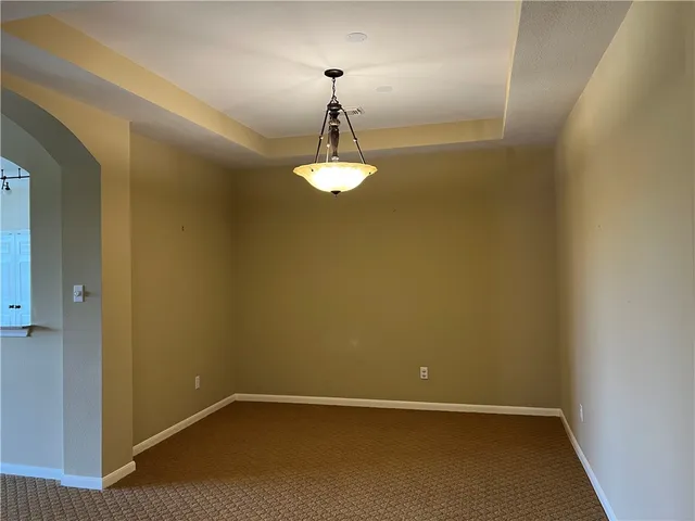 a view of an empty room with a chandelier fan