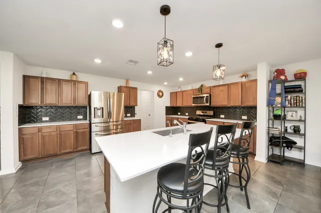 a kitchen with refrigerator a sink and chairs