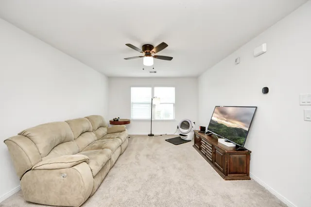 a living room with furniture a ceiling fan and a window