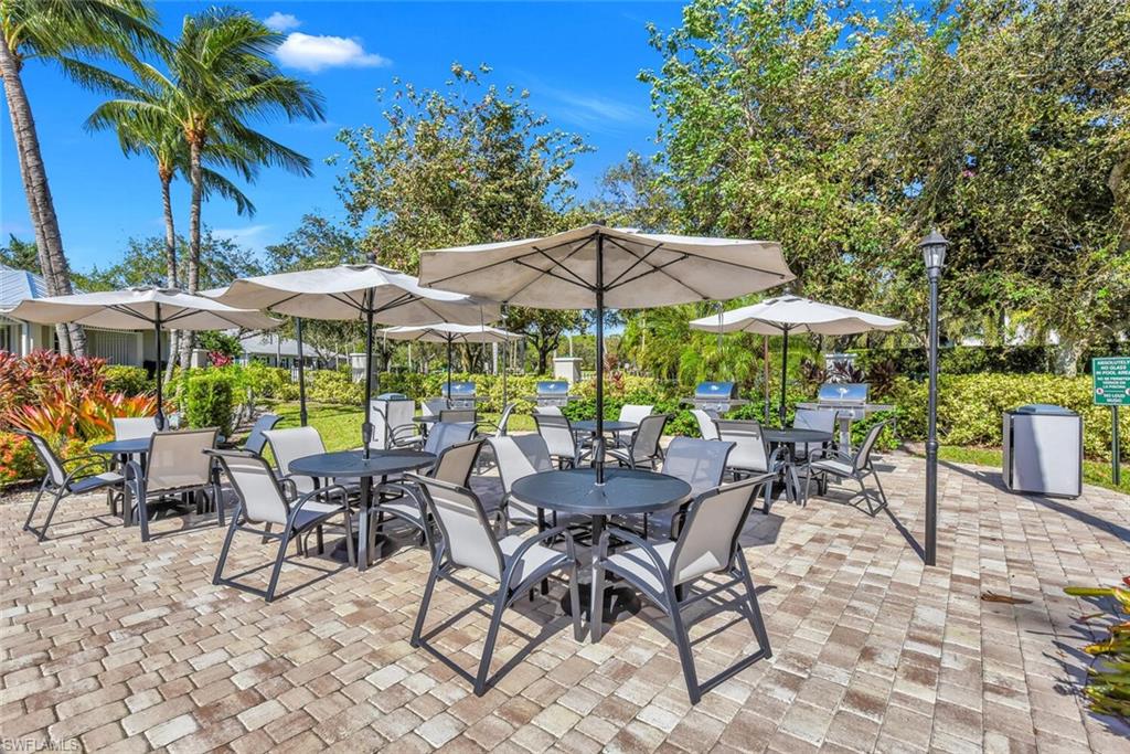 7880 Mahogany Run Lane, Unit 1614 Naples, FL 34113 - Photo 36 of 38 a view of patio with chairs and tables with an umbrella