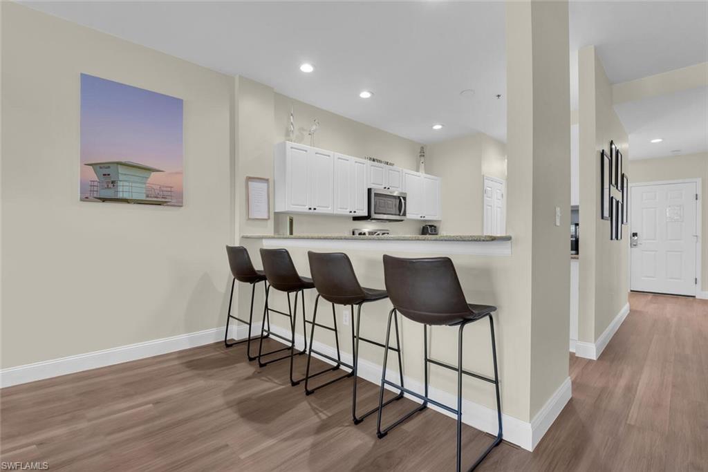 7880 Mahogany Run Lane, Unit 1614 Naples, FL 34113 - Photo 5 of 38 a kitchen with stainless steel appliances a dining table chairs and wooden floor