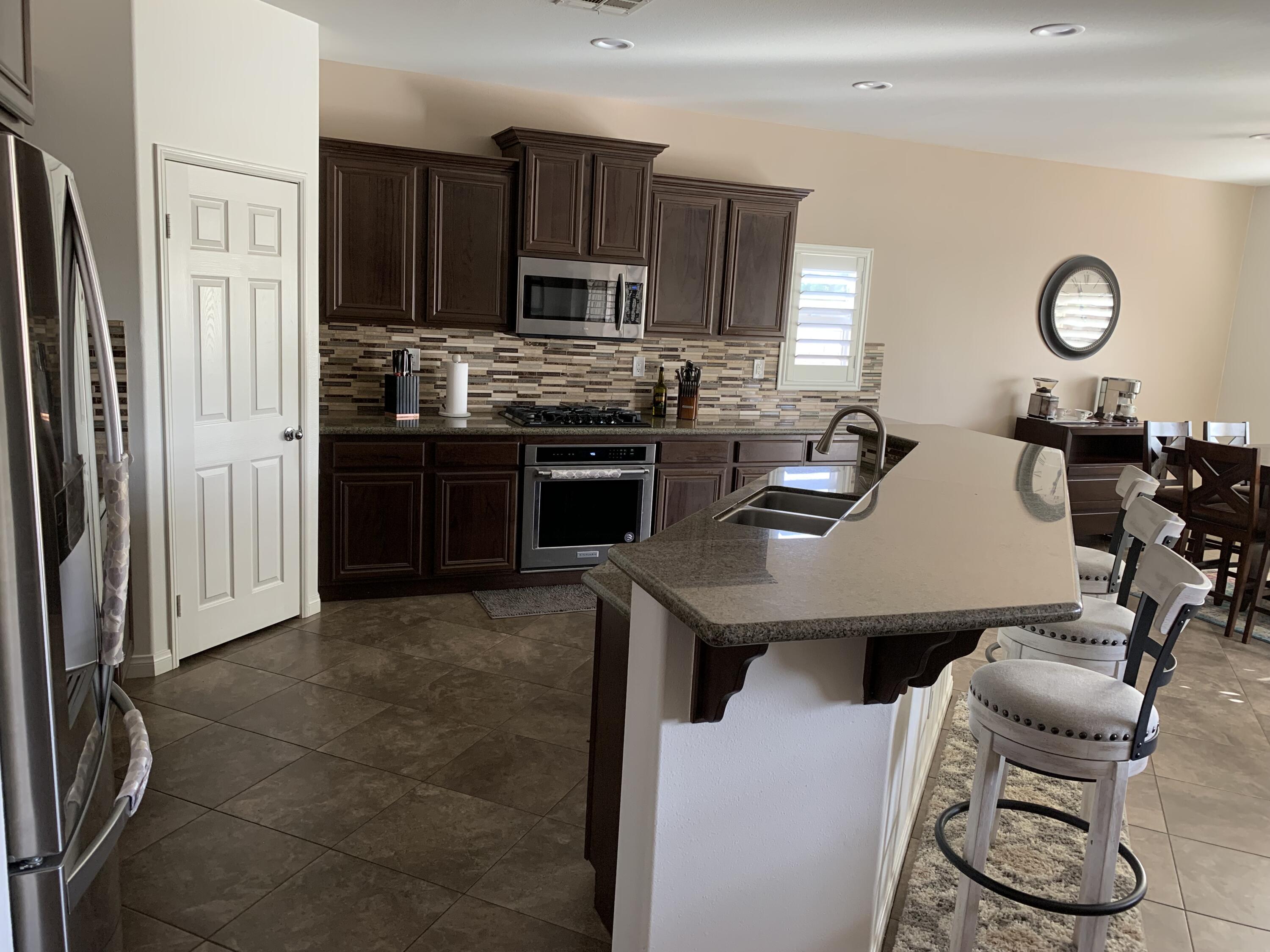 82515 Grass Flat Lane Indio, CA 92203 - Photo 3 of 44 a kitchen with granite countertop a refrigerator stove top oven dining table and chairs