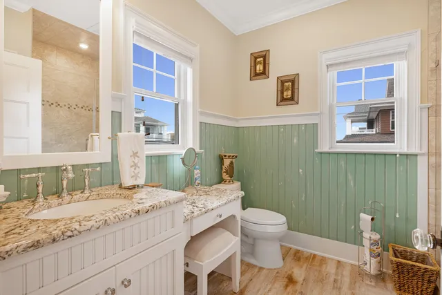a bathroom with a granite countertop sink a toilet a mirror and shower