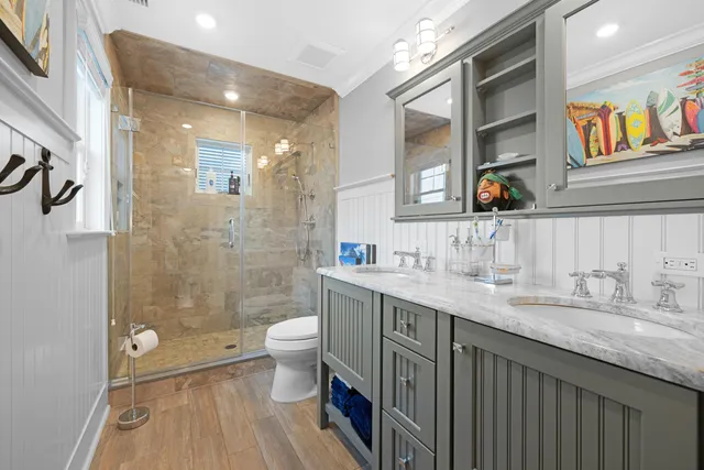 a bathroom with a granite countertop sink a toilet a mirror a vanity and shower