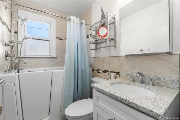 a bathroom with a granite countertop sink toilet and mirror