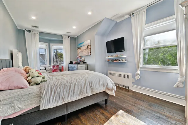 a bedroom with a large bed and a flat tv screen on dresser