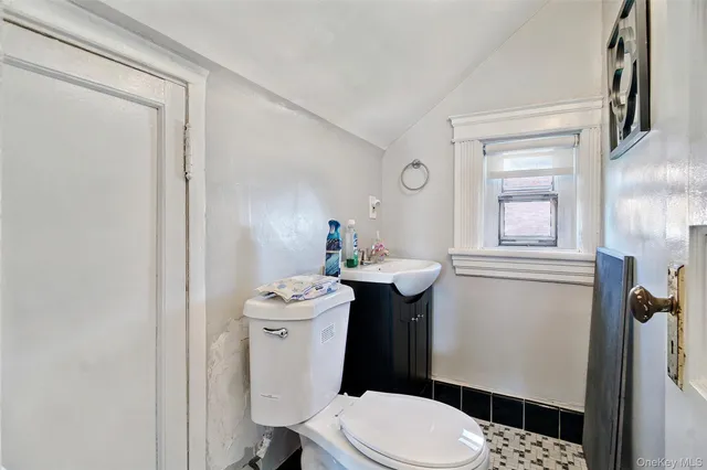a bathroom with a sink a toilet a window and vanity