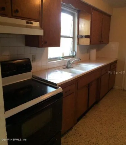 a kitchen with granite countertop stainless steel appliances a sink stove and cabinets