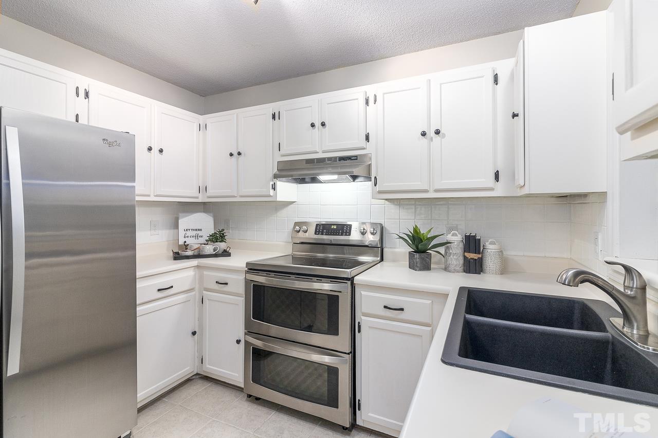 4704 Dillingham Court Raleigh, NC 27604 - Photo 4 of 10 Stainless steel appliances and white cabinets make this kitchen bright and inviting.